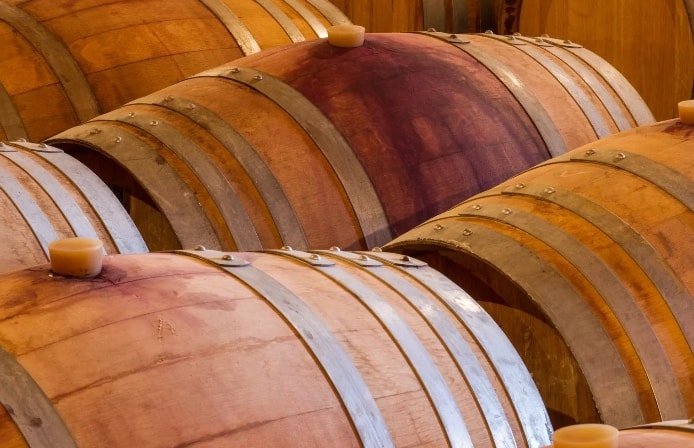 Rows of oak barrels aging in the winery cellar