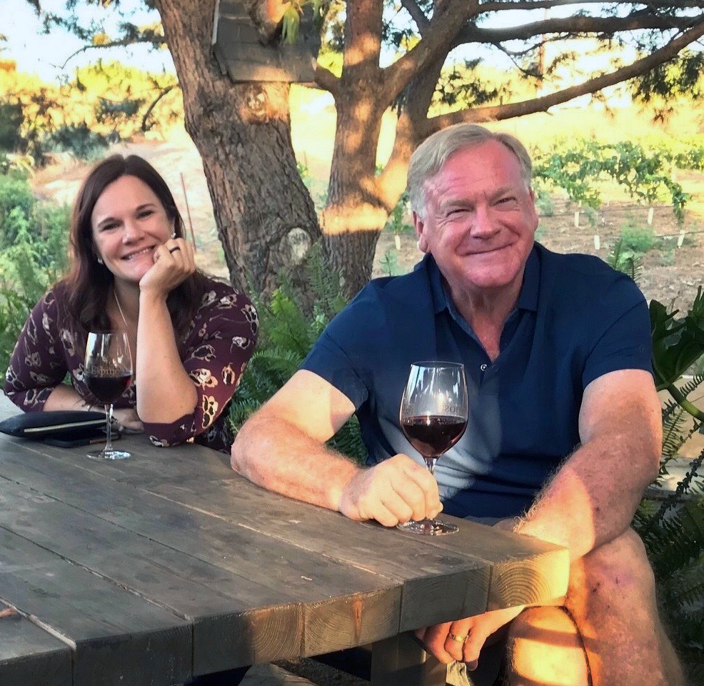 Father and daughter enjoying wine together at a vineyard table at golden hour